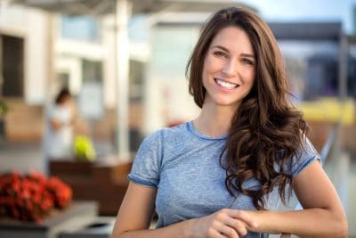 attractive woman standing on a pier shows off her amazing smile