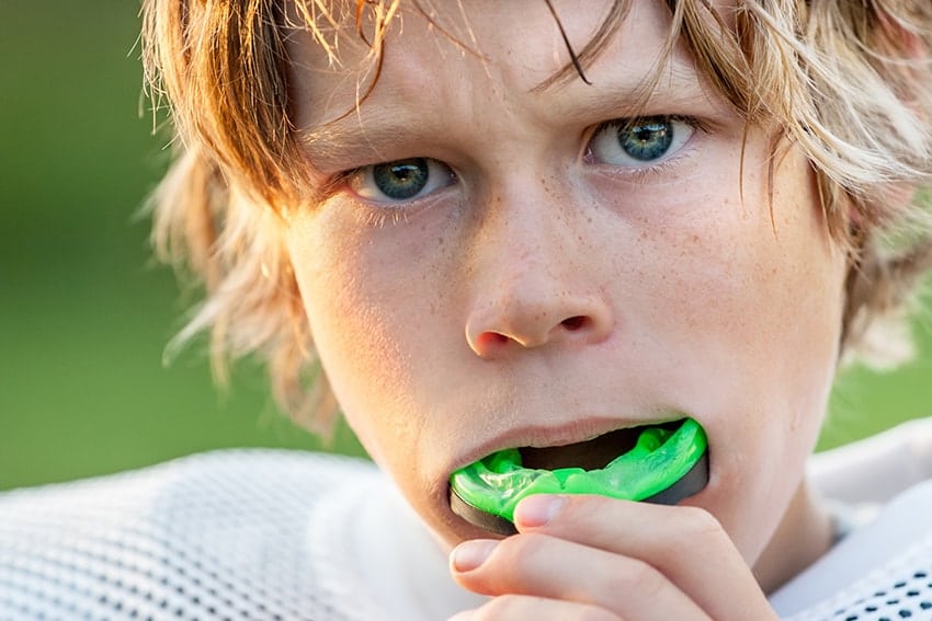 A young football playing putting a mouthguard in, ready for the game! These professional mouth guards not only protect your teeth, they can improve your performance.