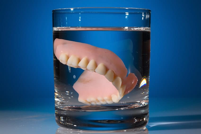Removable dentures sitting in a glass overnight to clean