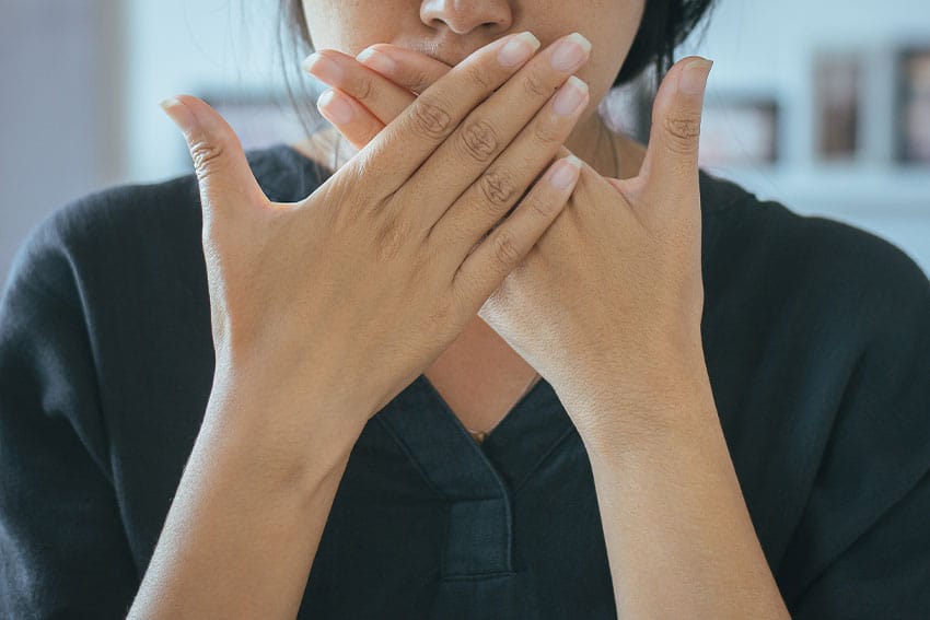 woman covering up her mouth due to bad breath