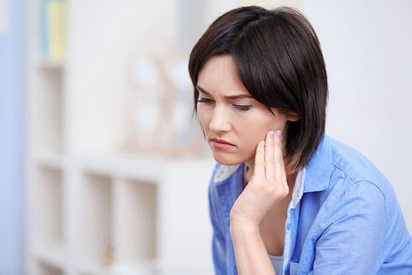 young woman massaging her jaw due to TMJ
